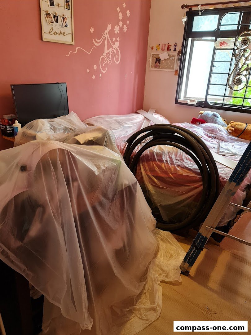 A room with items covered in plastic, including a bed and a ladder.