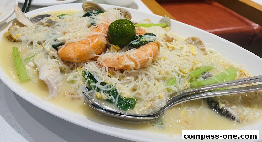A close-up of a delicious seafood noodle dish with prawns, fish, and clams.