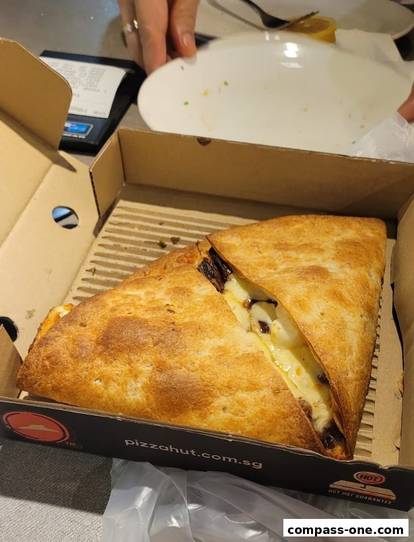 A delicious-looking pizza slice in a Pizza Hut box, ready to be enjoyed.