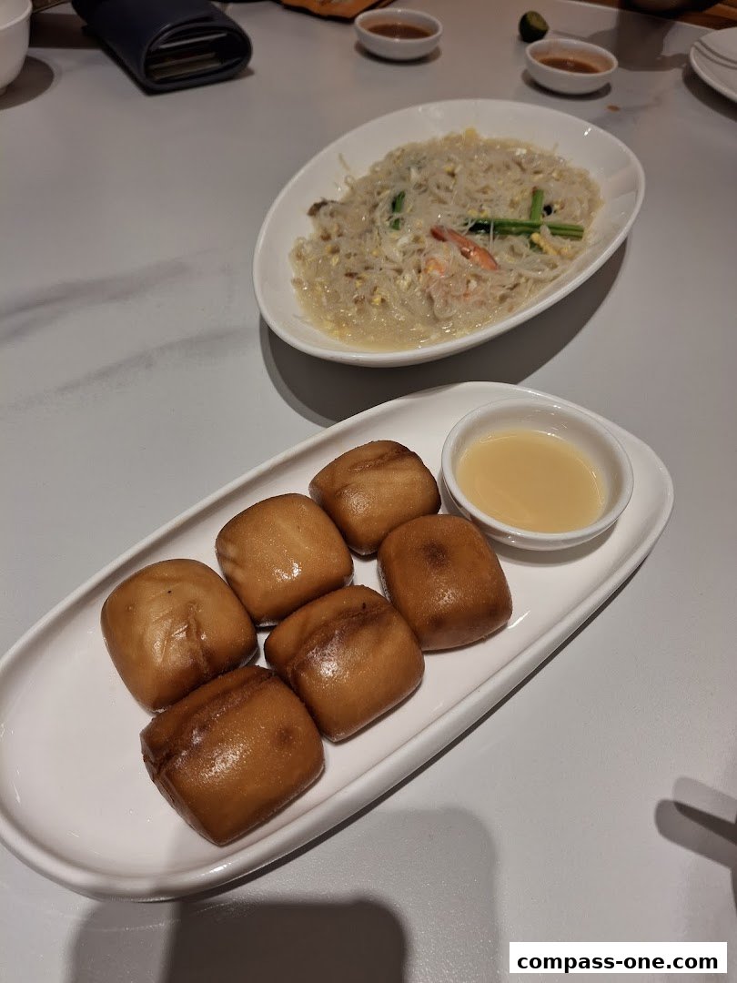 A plate of fried mantou buns with a dipping sauce and a dish of noodles with shrimp.