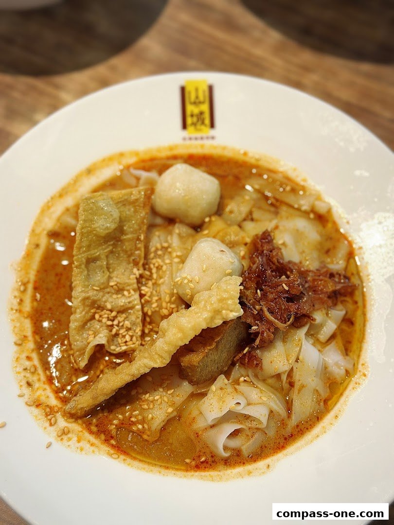 A close-up of a delicious bowl of Ipoh-style noodles with fish balls and fried bean curd.