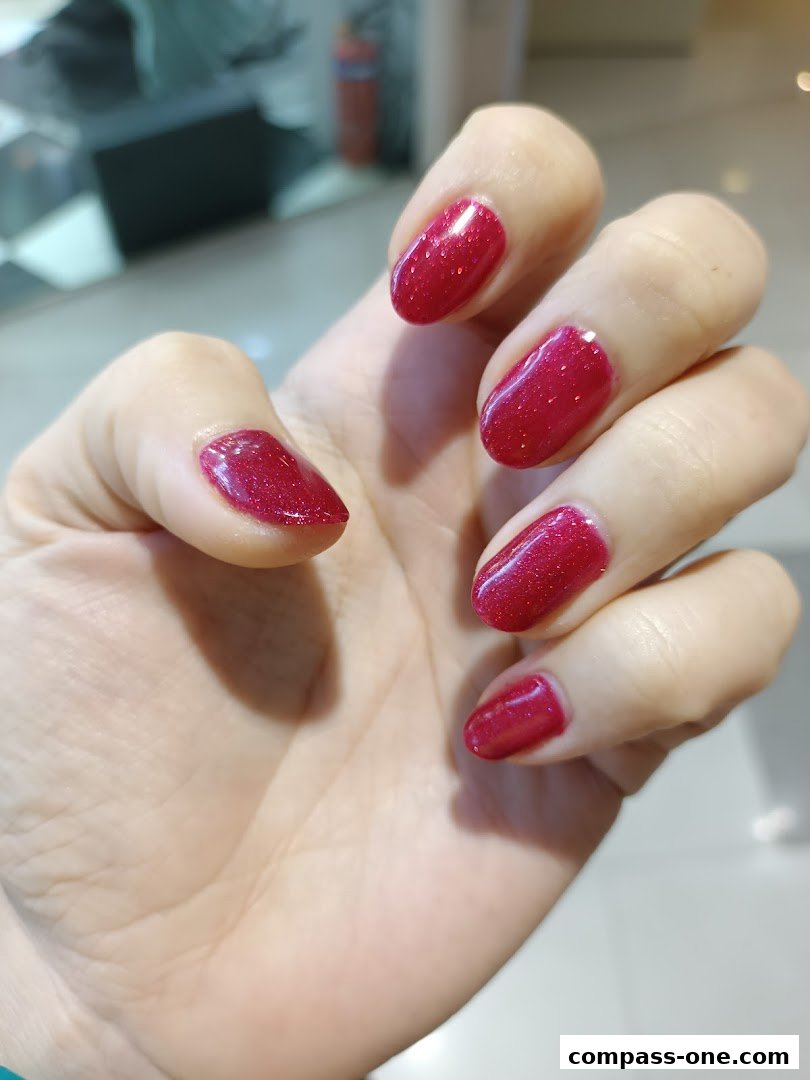 A close-up of a hand with perfectly manicured, sparkling red nails.