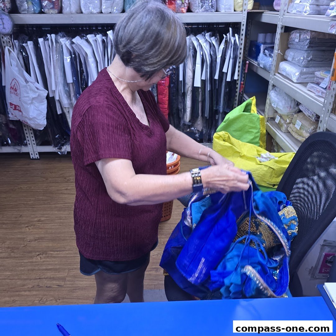 A woman is sorting through blue garments in a dry cleaning and laundry service shop.