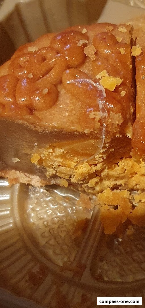 A close-up of a golden-brown mooncake with intricate patterns, showing its flaky crust and filling.