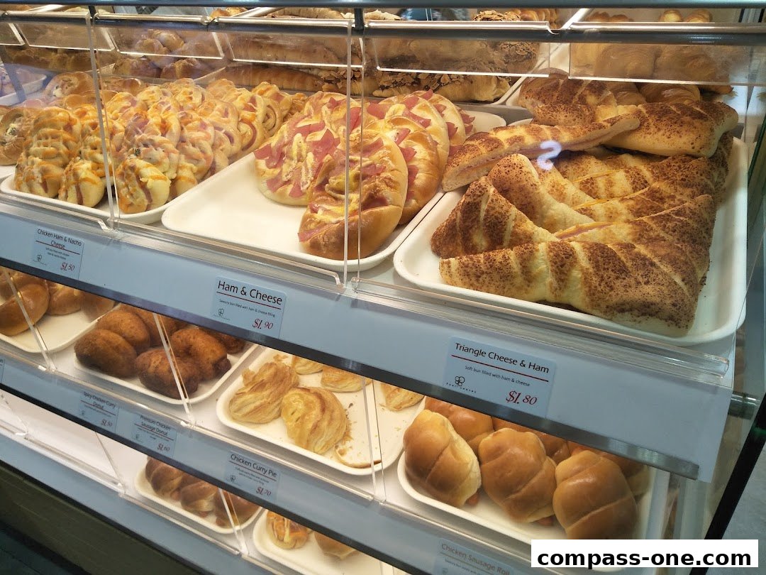 A display case filled with various baked goods, including savory buns and pastries.