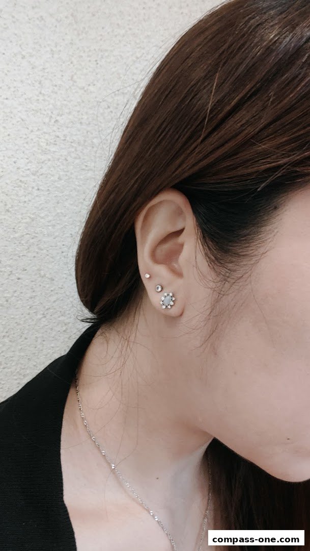 A close-up of a woman's ear adorned with delicate stud earrings and a floral-shaped earring.