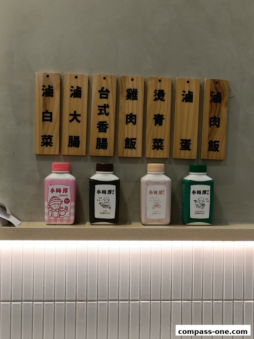 Wooden signs with Chinese characters above bottles of drinks on a shelf.