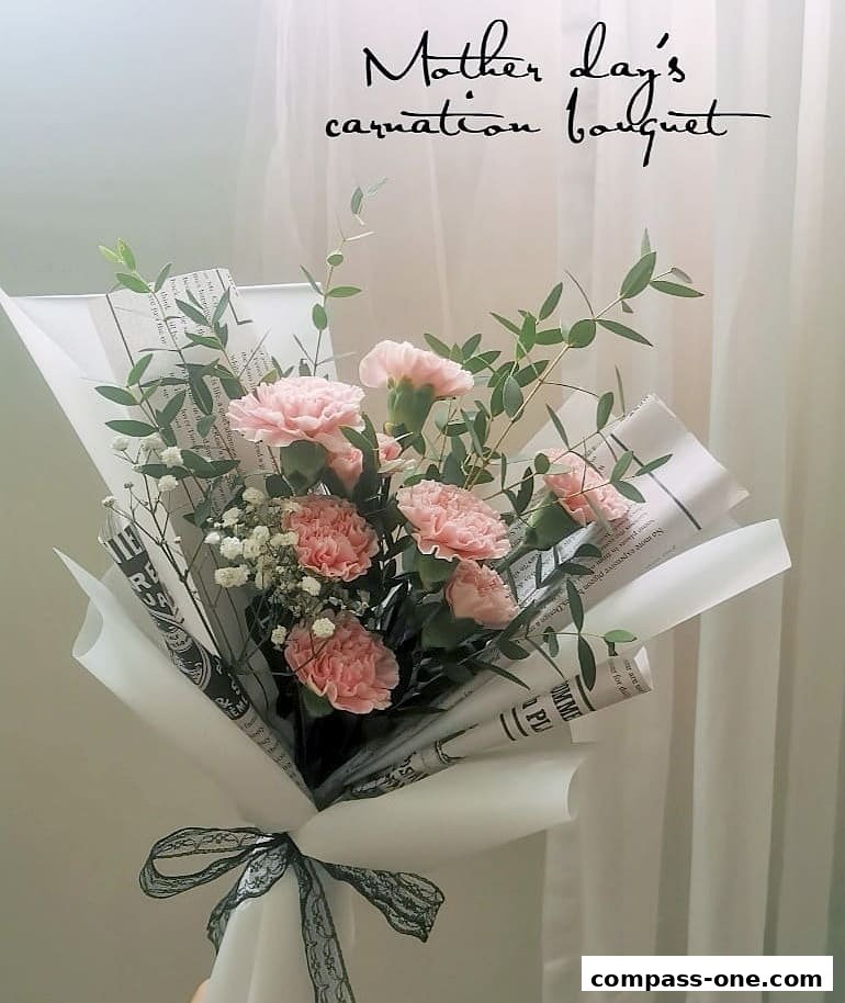 A beautiful pink carnation bouquet with eucalyptus, wrapped in white paper and newspaper, tied with a black ribbon.