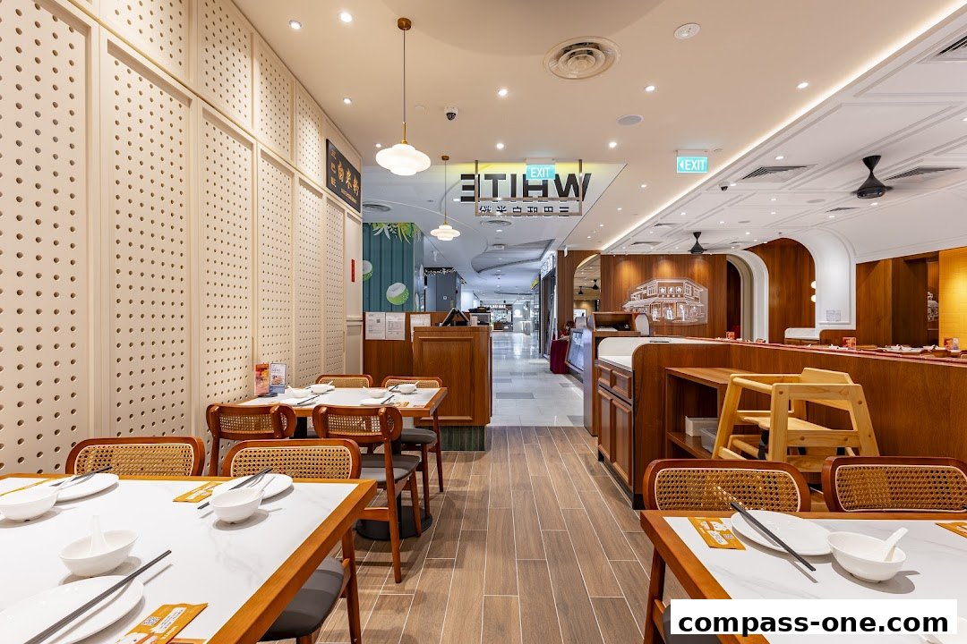 Interior view of a modern restaurant with wooden furniture and white tables set for dining.