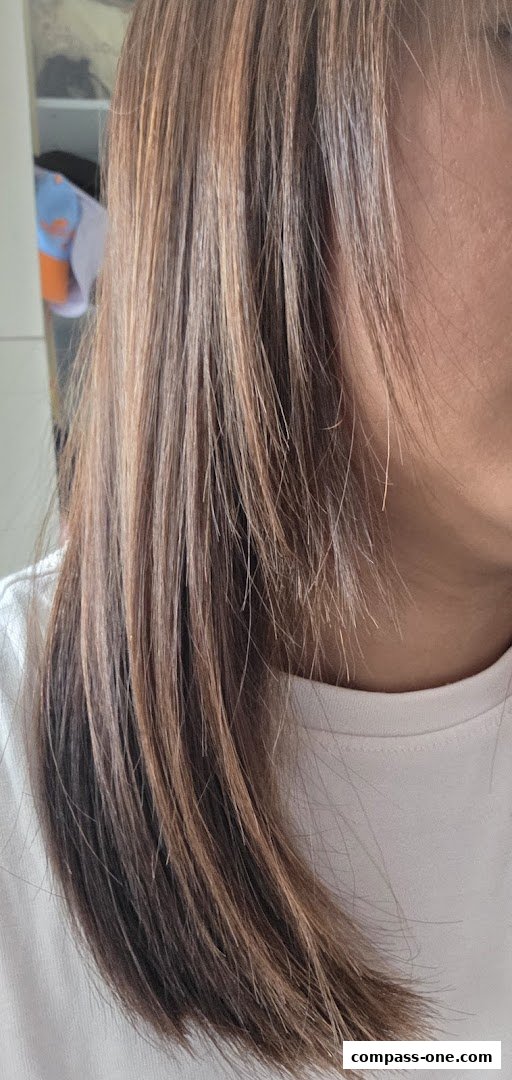 Close-up of a person's hair with highlights, showing a new hairstyle.