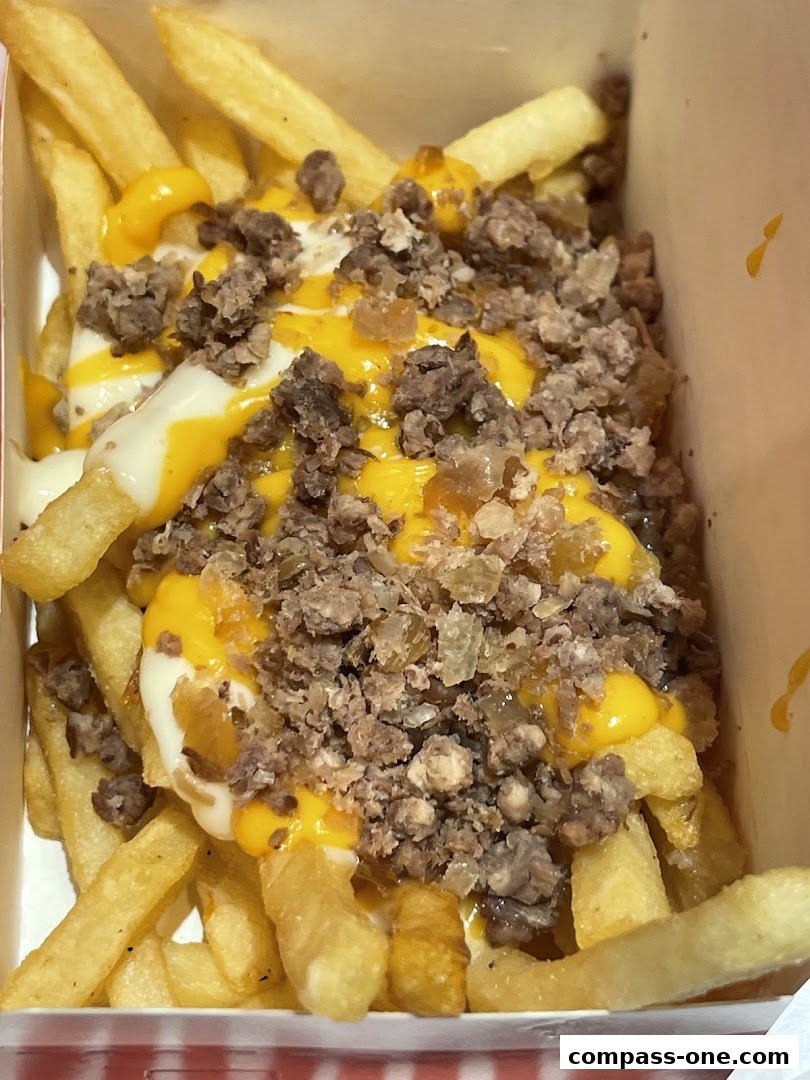 A close-up shot of loaded fries topped with cheese sauce and minced meat.