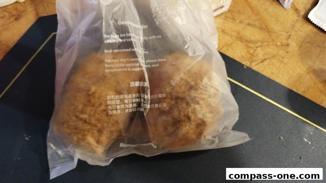 A plastic bag containing two fluffy buns with a savory topping, likely from Four Leaves bakery.