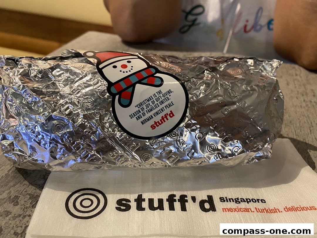 A foil-wrapped food item with a snowman sticker and a napkin from Stuff'd.