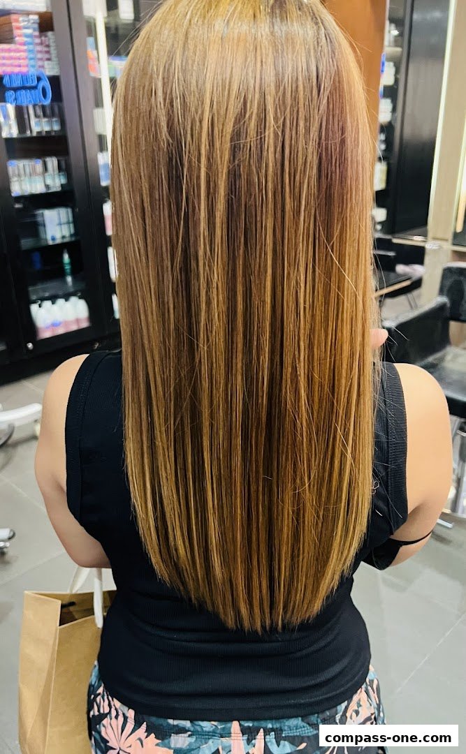 A person with long, straight, blonde-highlighted hair in a salon.