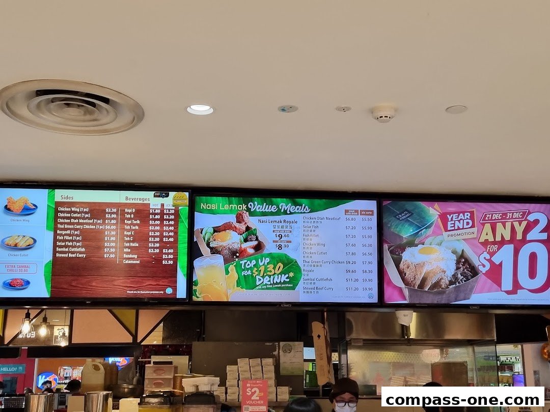Digital menu boards displaying Nasi Lemak meals, sides, and beverages with prices.