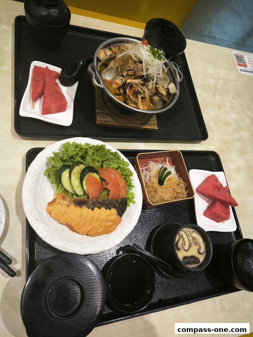 A delicious Japanese meal featuring grilled fish, clam soup, and fresh fruit.