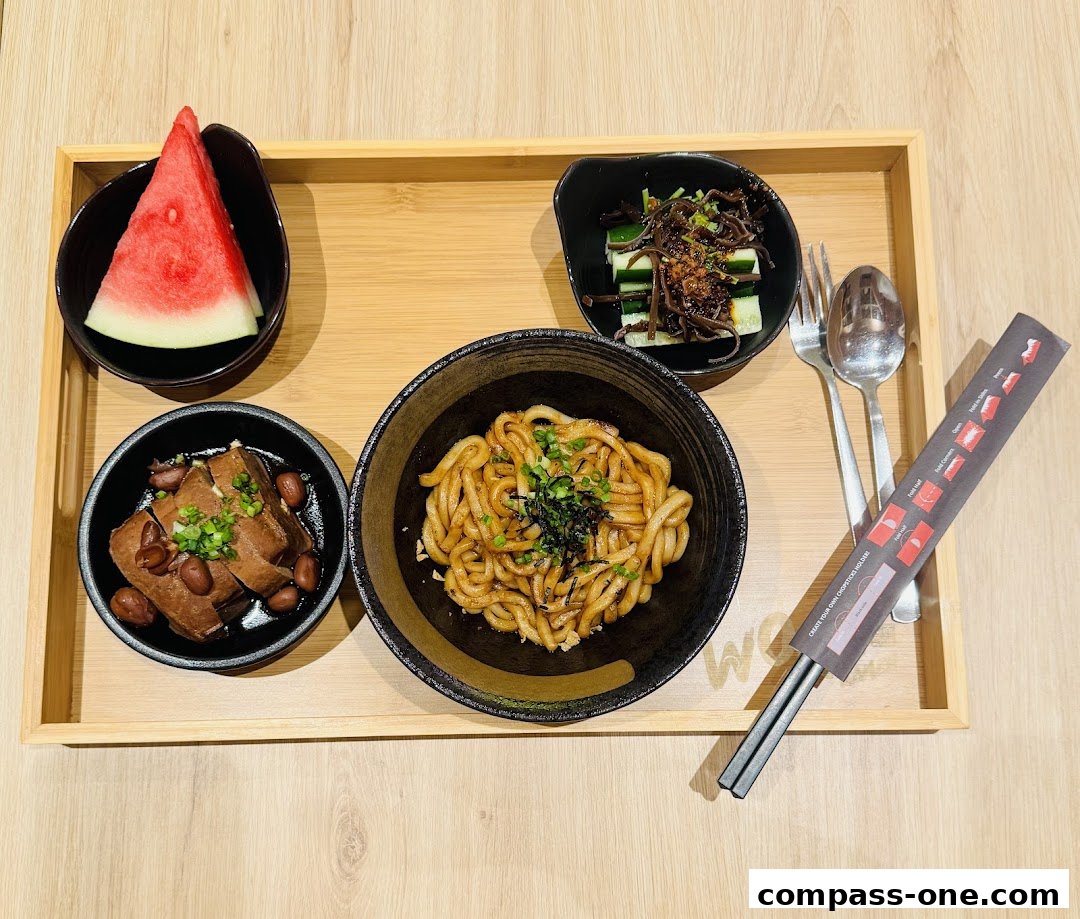 A delicious meal featuring noodles, side dishes, and watermelon served on a wooden tray.