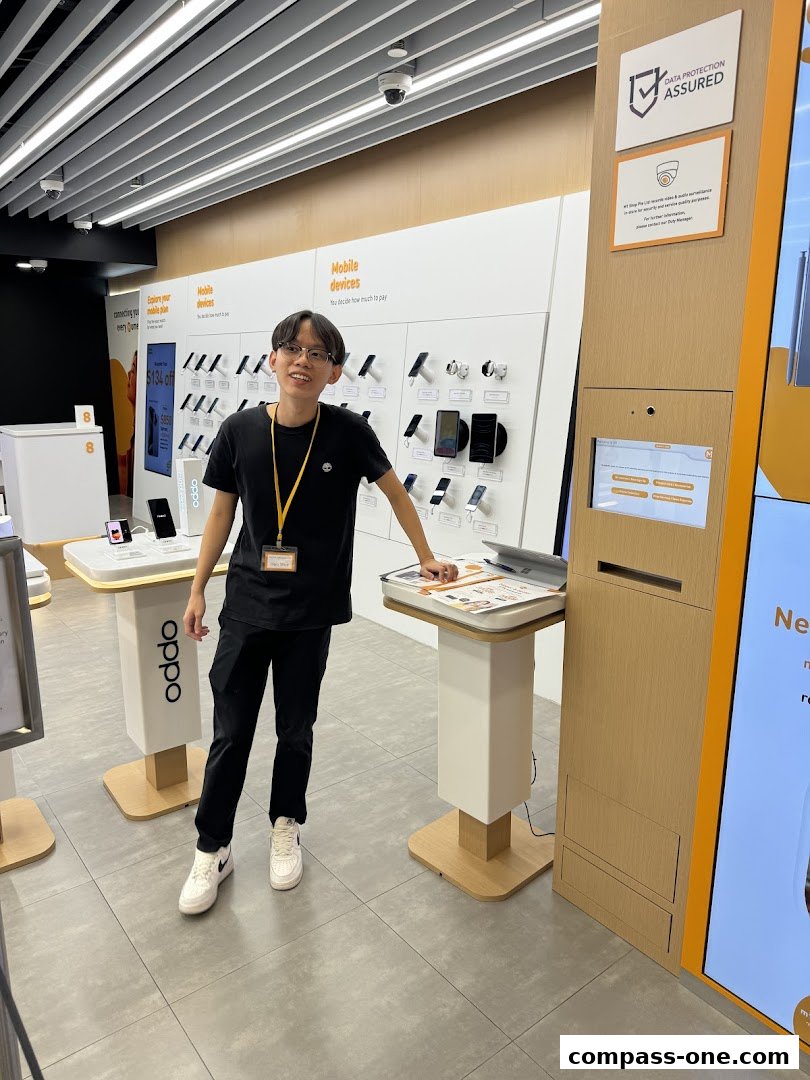 A young man stands in a brightly lit mobile phone shop, showcasing various devices.