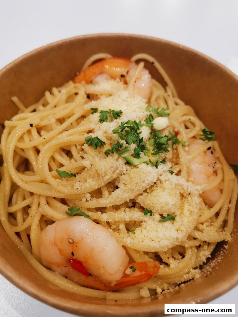 A close-up of a bowl of spaghetti with shrimp, cheese, and parsley.