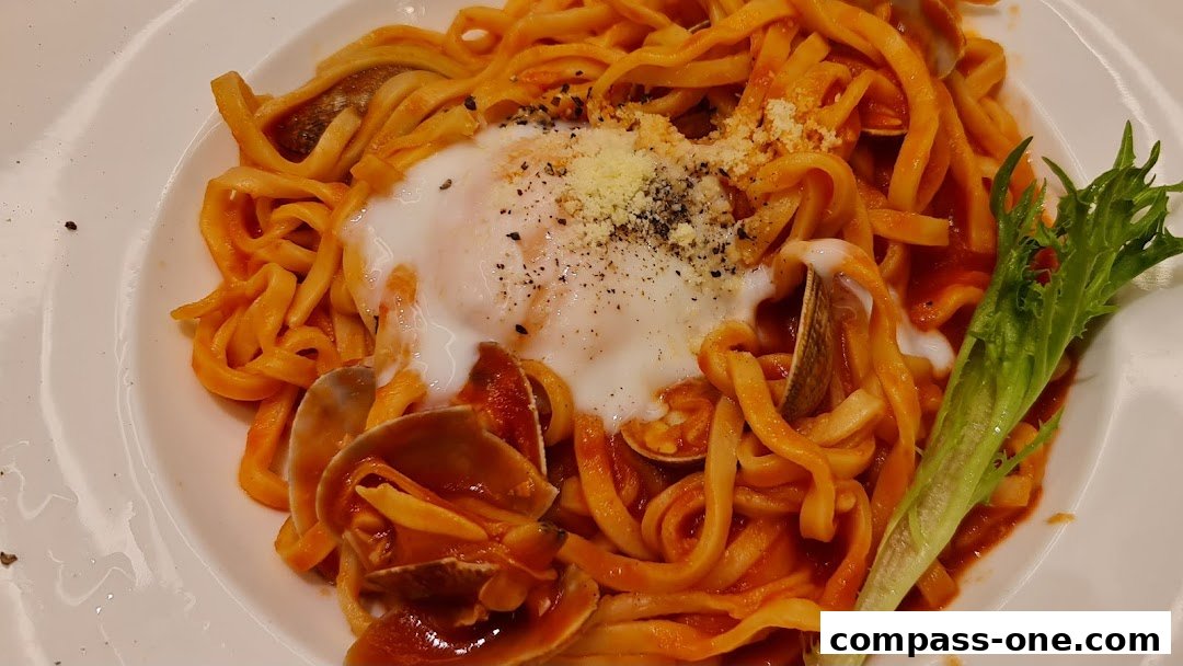 A plate of pasta with clams, a poached egg, and grated cheese, garnished with a lettuce leaf.