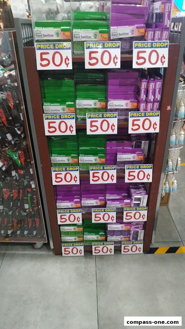 Shelves stocked with hand sanitizer bottles, many with 'Price Drop 50¢' signs.