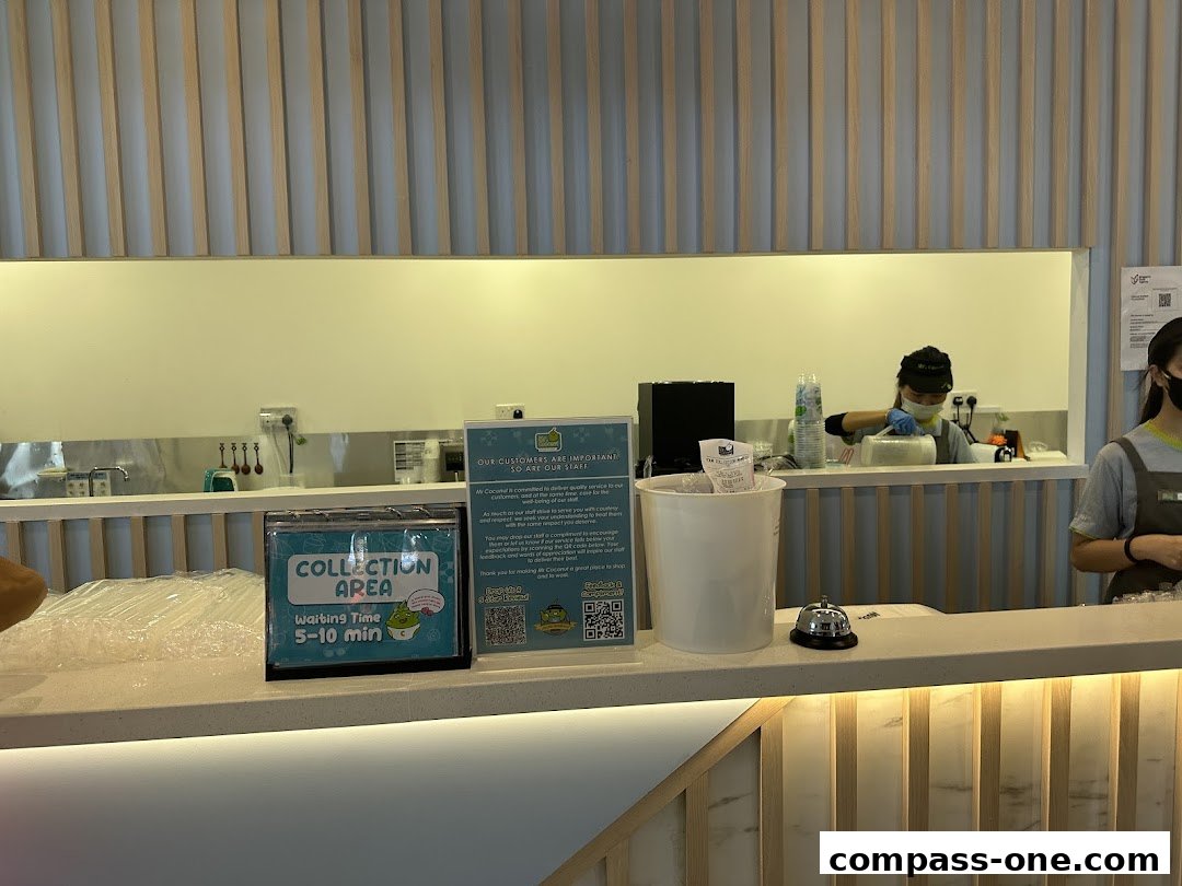 A counter at Mr. Coconut with a collection area sign and staff preparing drinks.