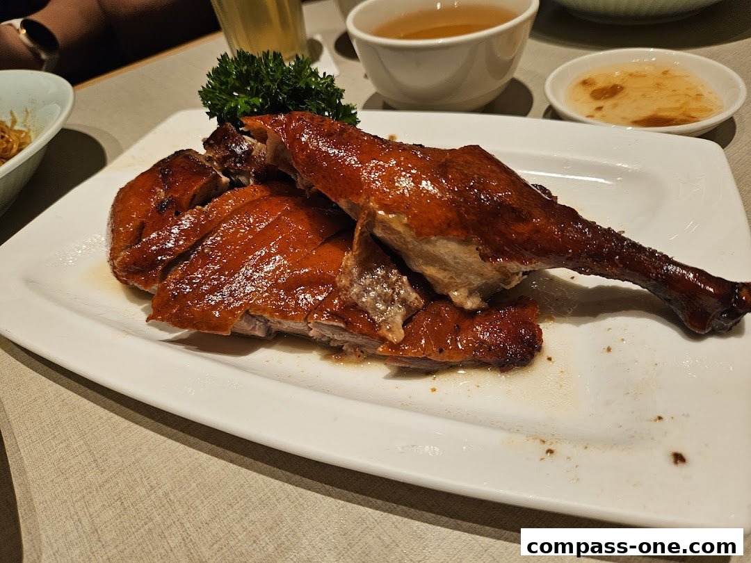 A plate of roasted duck with crispy skin, garnished with parsley, served with dipping sauce and tea.