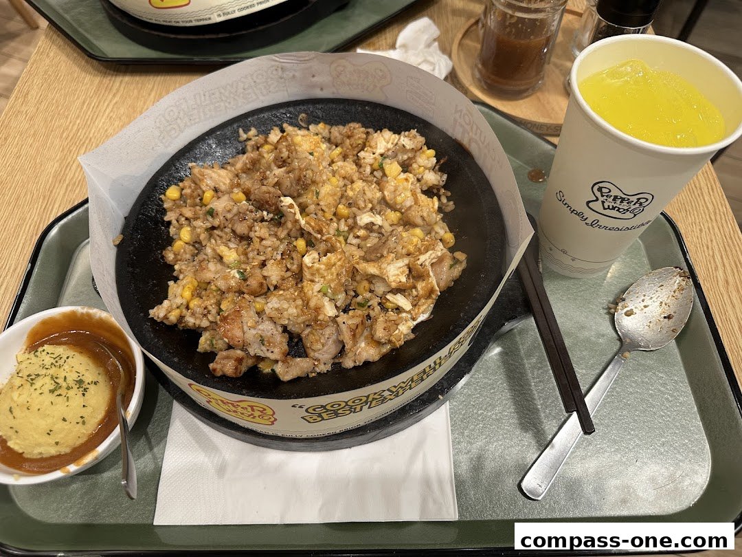A sizzling hot plate of chicken and rice with a side of mashed potatoes and a drink.