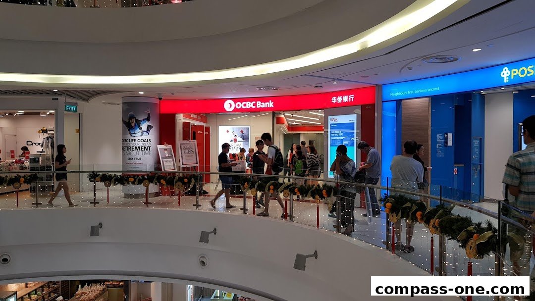 The OCBC Bank branch entrance with customers waiting and promotional posters.
