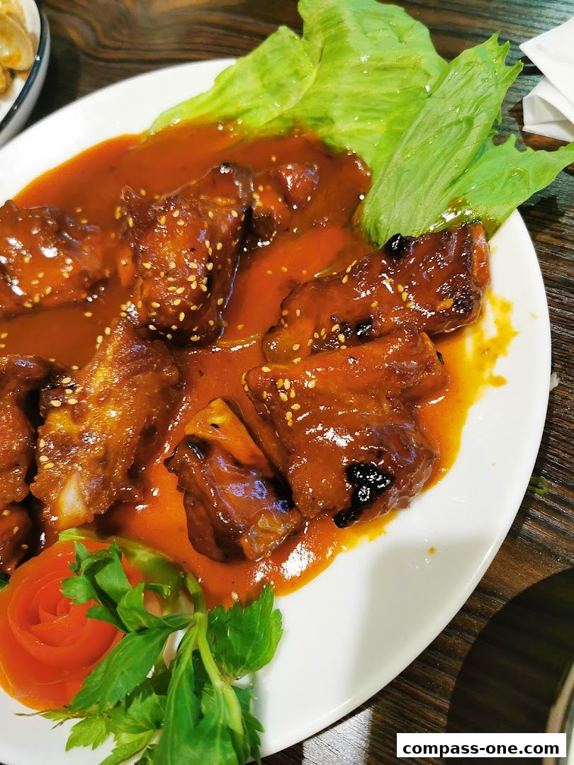 A plate of succulent grilled ribs in a rich, savory sauce, garnished with lettuce and a tomato rose.