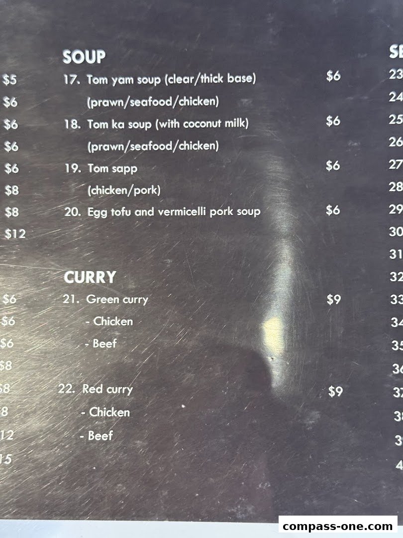 A close-up of a menu featuring Thai soups and curries with prices.