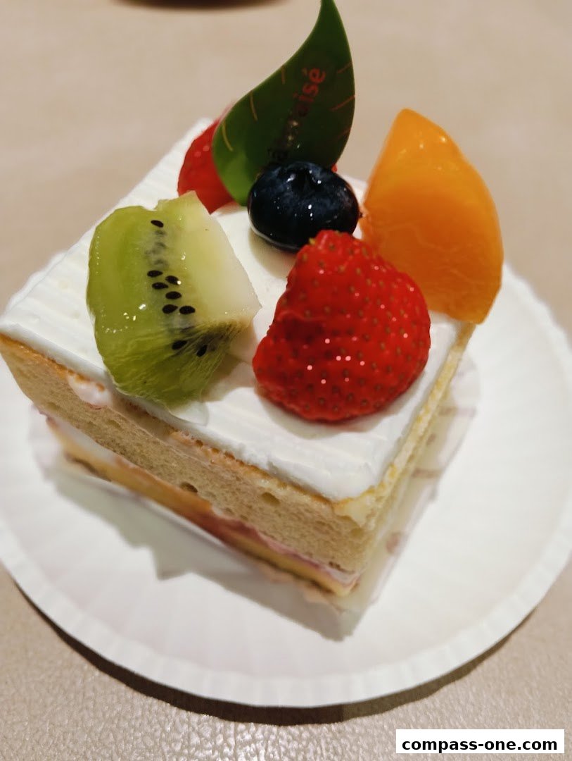 A slice of cake topped with fresh fruits like kiwi, strawberry, blueberry, and peach.