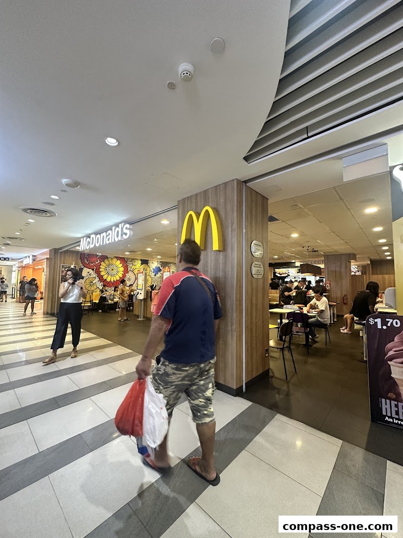 People walking past a McDonald's restaurant with its iconic golden arches visible.