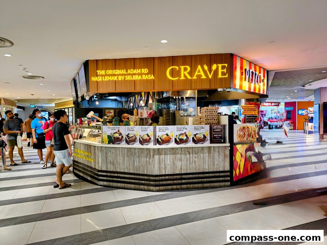 A Crave Nasi Lemak stall with customers queuing, showcasing food displays and signage.