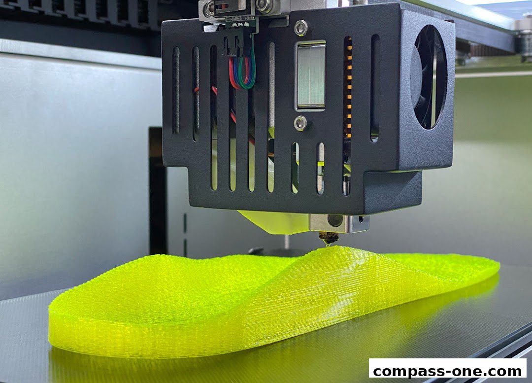A 3D printer is creating a bright yellow insole with intricate layering.