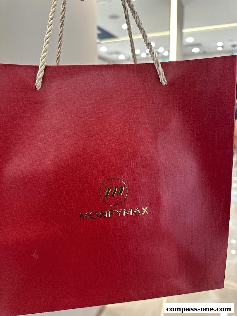 A red shopping bag with the MoneyMax logo and gold lettering.