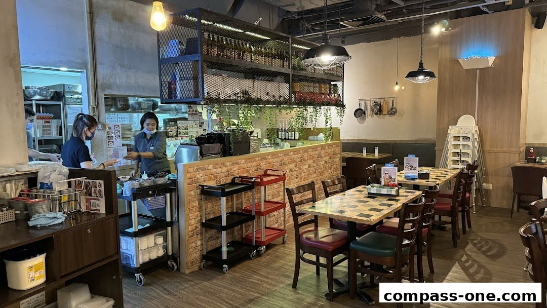 Interior view of a restaurant with tables, chairs, and staff working behind the counter.