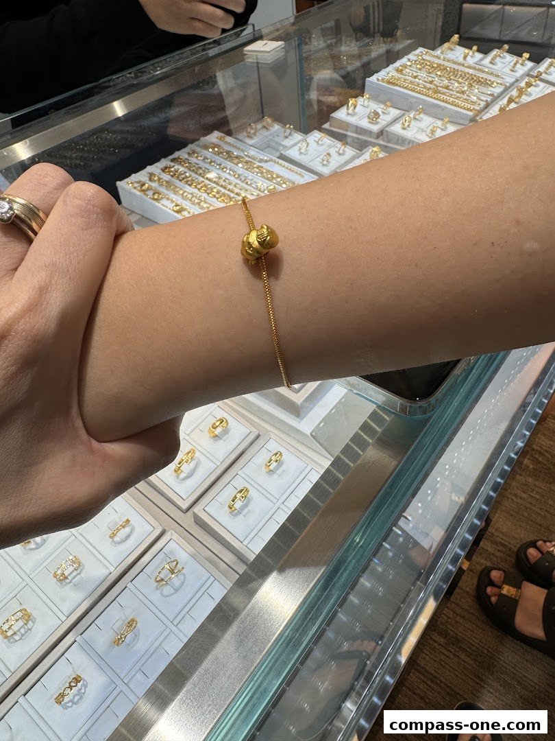 A person tries on a gold bracelet with a charm in a jewelry store display.