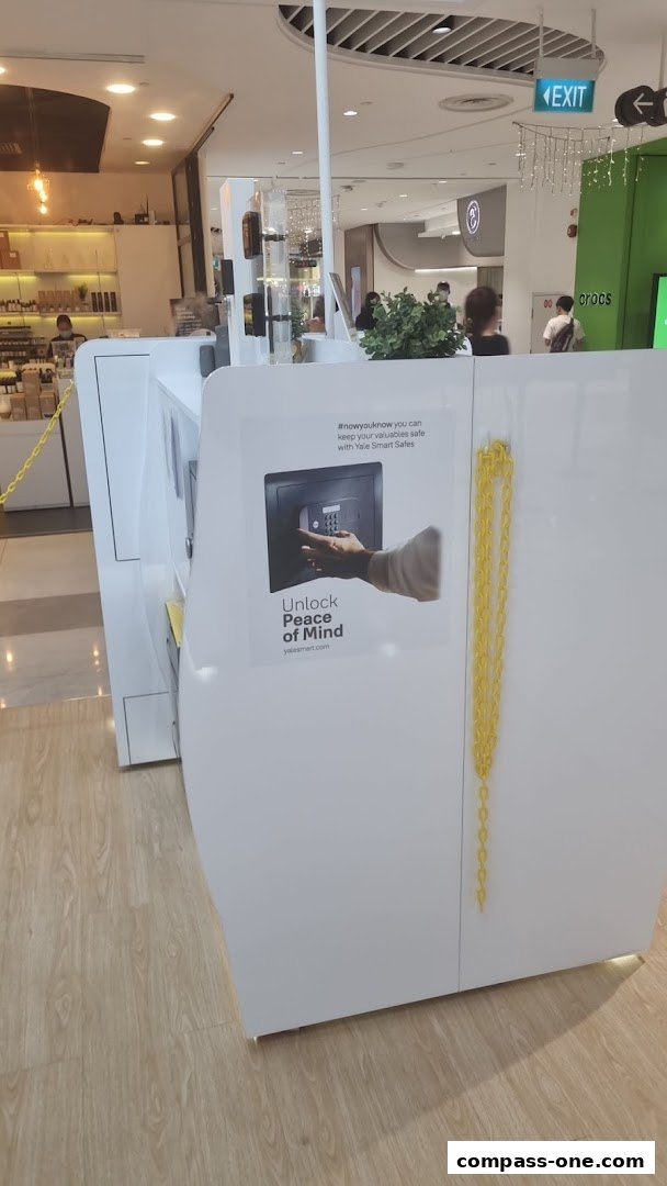 A white retail kiosk with a poster advertising Yale Smart Safes and a yellow chain.