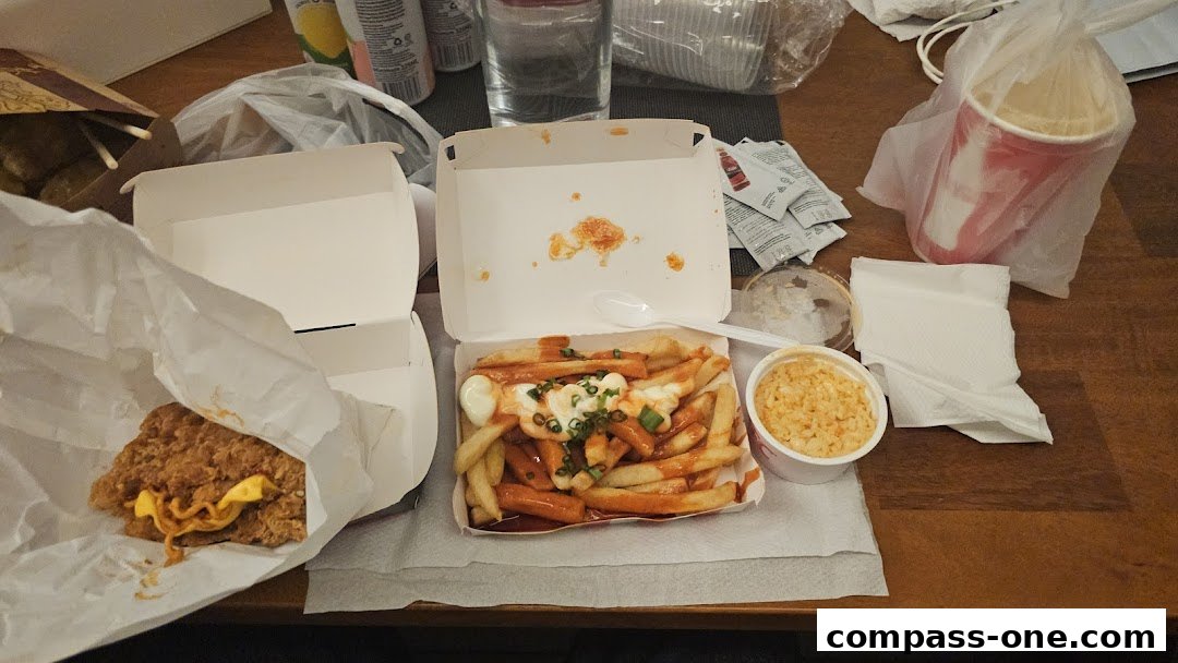 A table laden with KFC takeout food, including fried chicken, loaded fries, and a drink.
