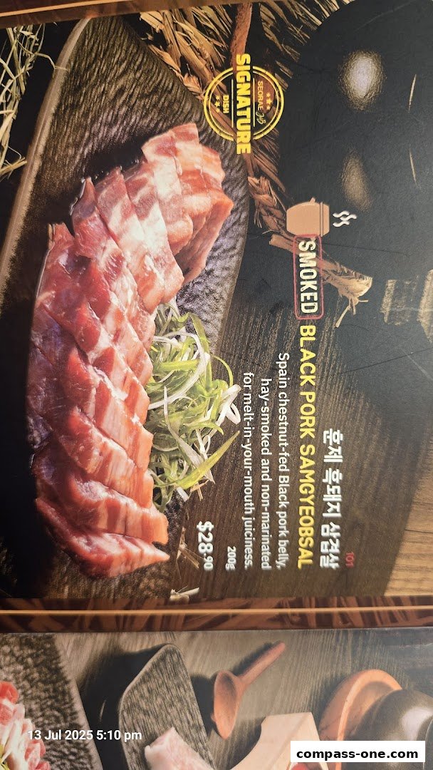 A close-up of a signature dish featuring sliced smoked black pork belly with green onions.