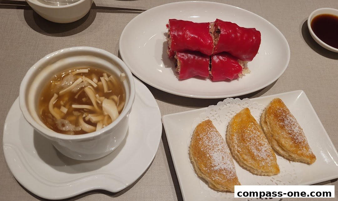 A close-up of three Chinese dishes: soup, red rolls, and pastries, served on white plates.