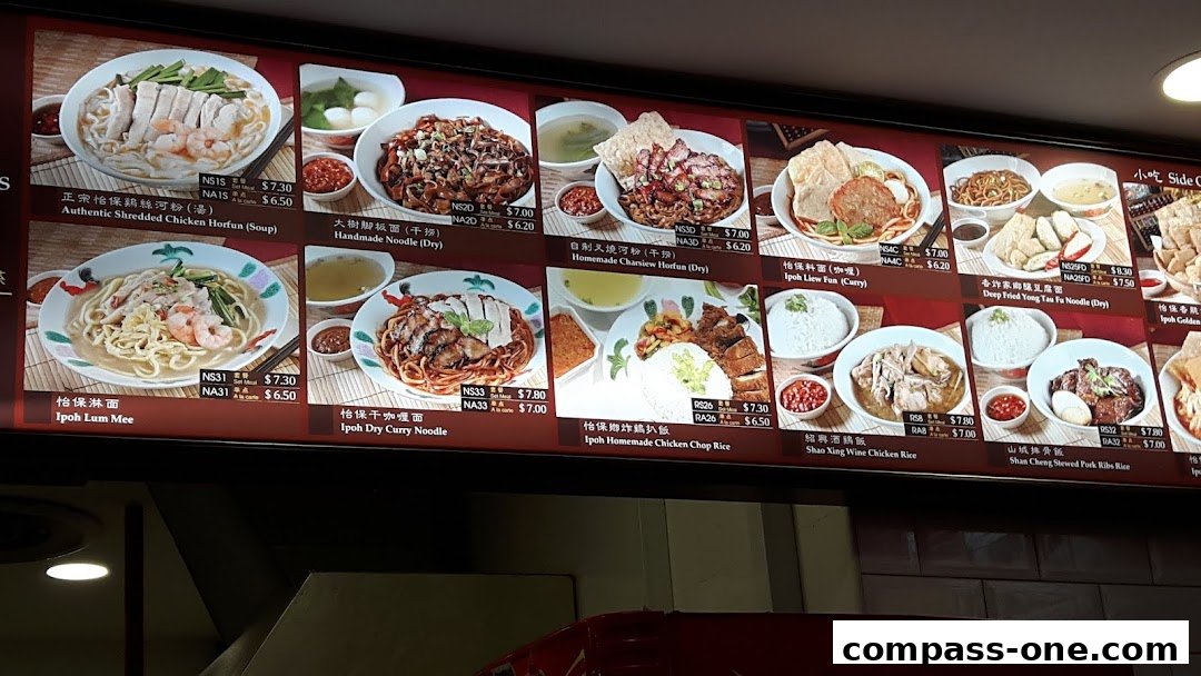 A digital menu board displaying various Ipoh-style noodle and rice dishes with prices.