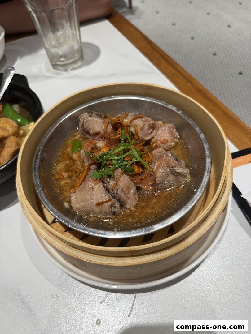 A close-up of a steamed dish with meat and herbs in a bamboo steamer.