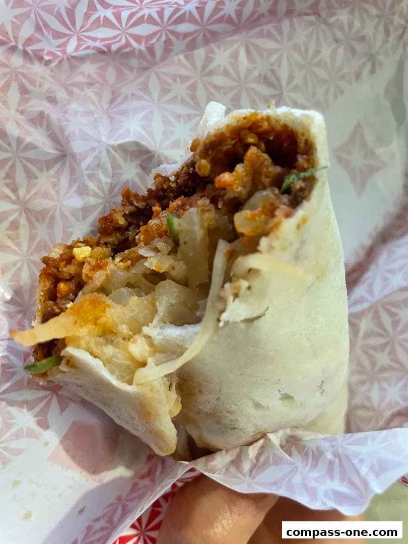 A close-up shot of a delicious-looking burrito, wrapped in paper with a geometric pattern.