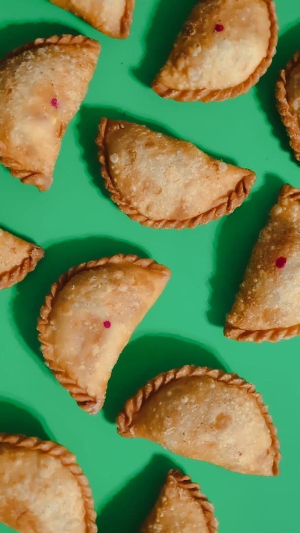 Golden-fried pastries, possibly curry puffs, arranged on a vibrant green background.