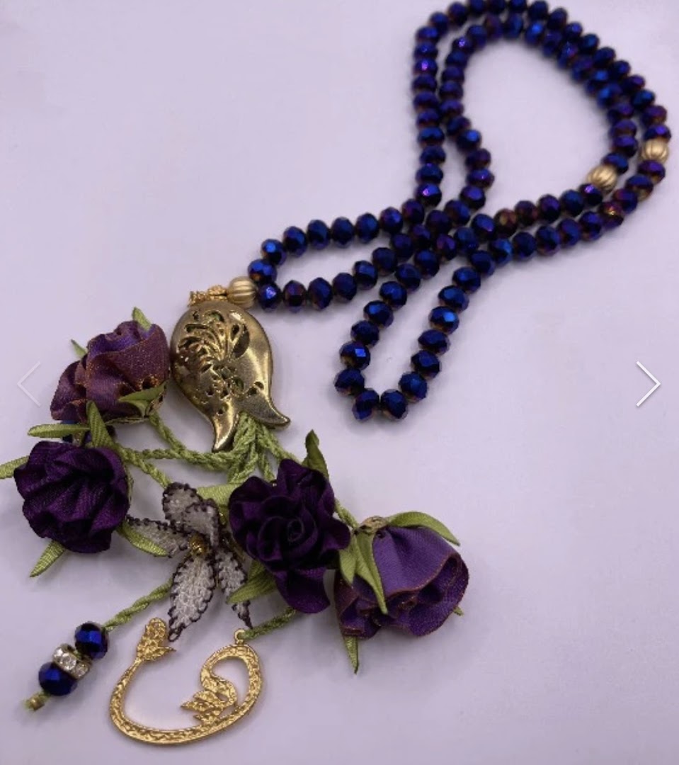 A beautiful blue beaded tasbih with purple floral and gold charm embellishments on a white background.