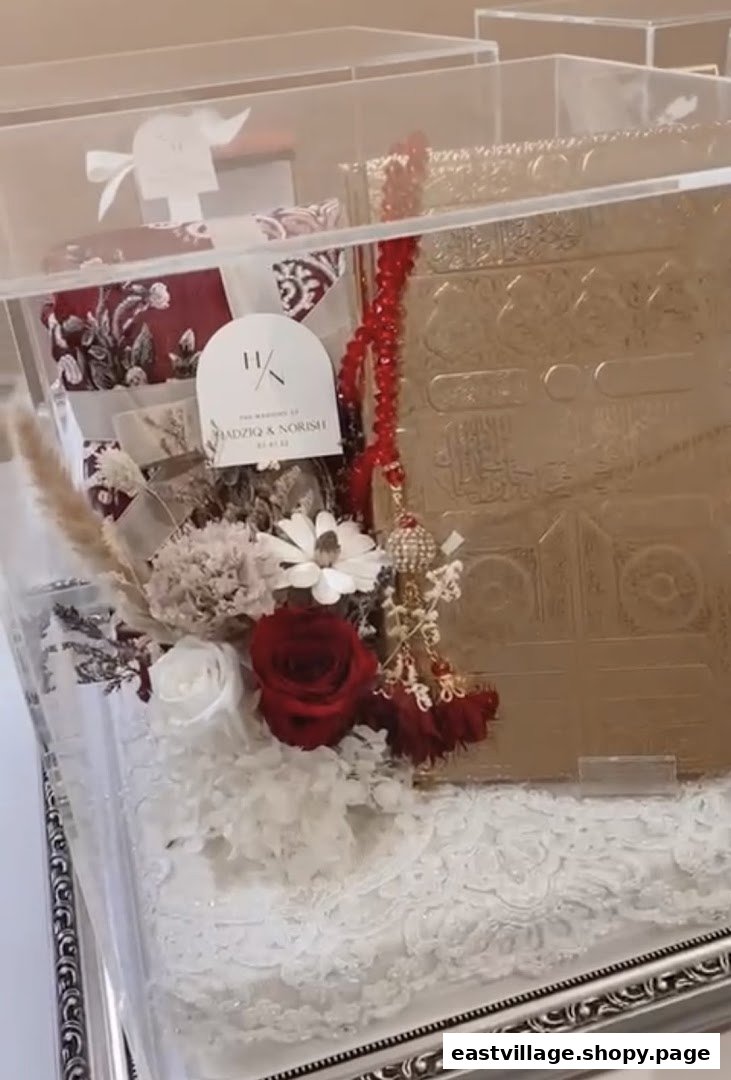 A beautifully arranged Islamic gift set featuring a golden Quran, prayer mat, tasbih, and floral decor in a clear display box.