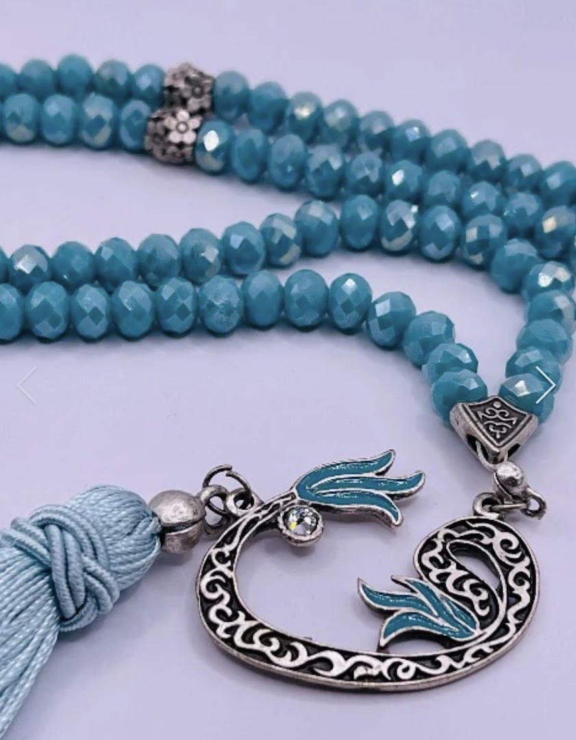 Close-up of beautiful blue faceted prayer beads with an ornate silver and enamel tassel.