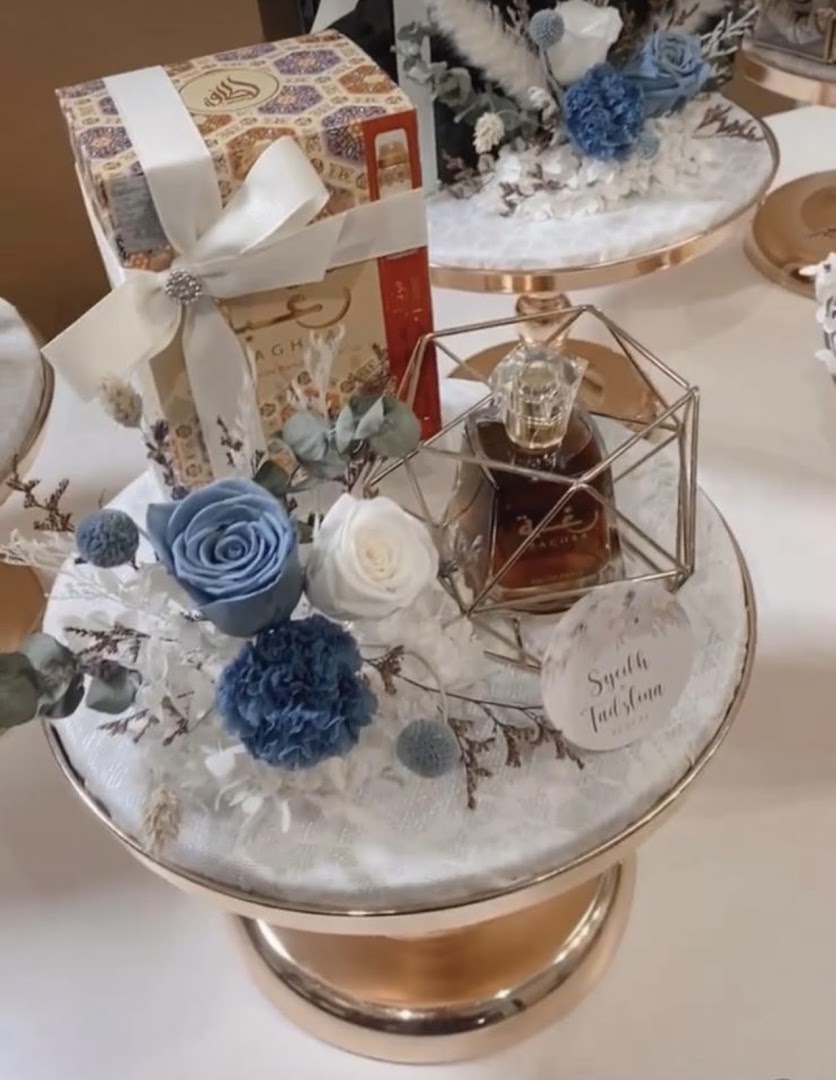 An elegant gift set featuring a perfume bottle, blue and white floral arrangements, and a decorative gift box.